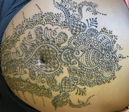 Intricate full baby-bump henna design in dense paisley and floral mehndi