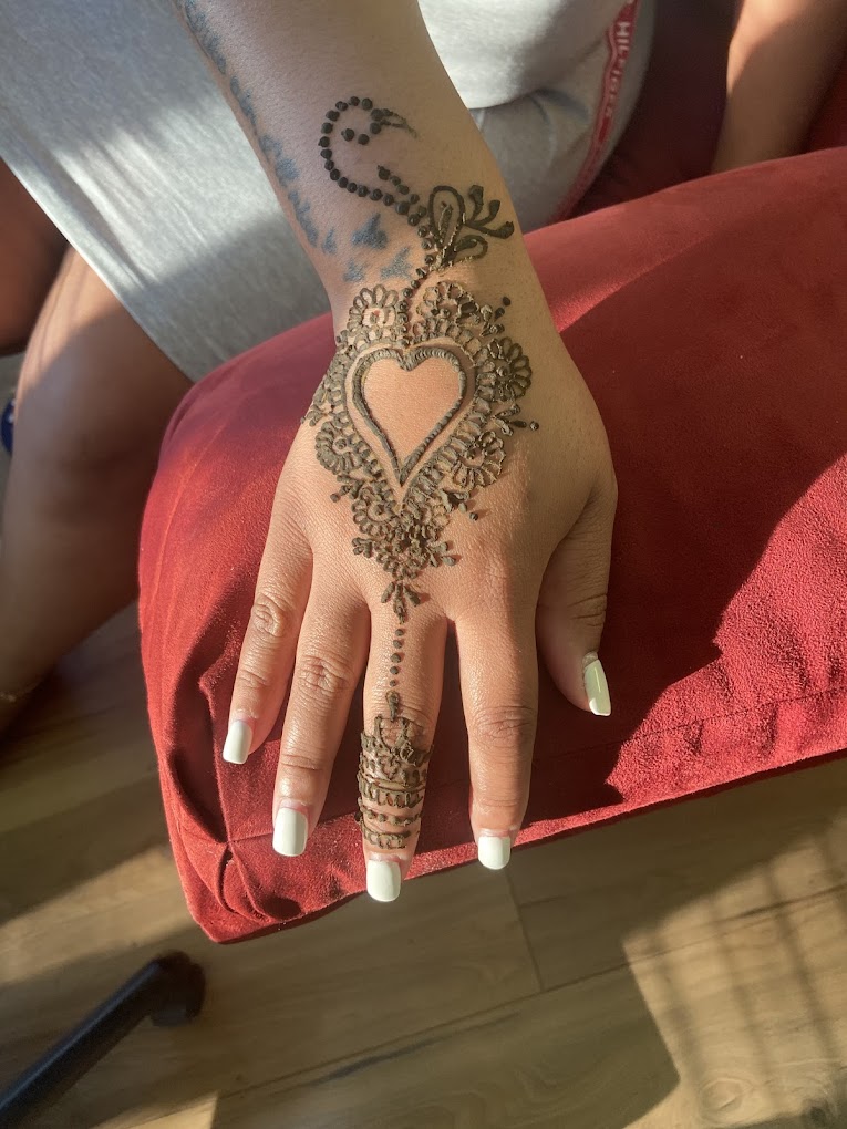 Freehand henna design with a heart and floral mehndi pattern on a client's hand